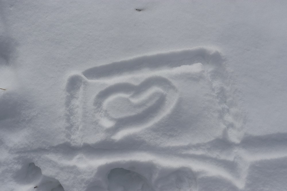 A heart drawn in the snow with a square around it. 
